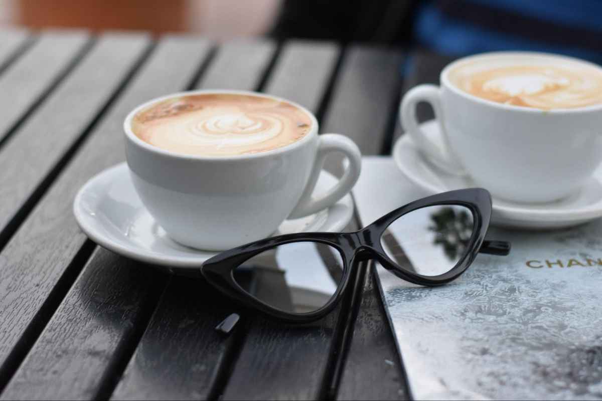 black eyeglasses placed beside cups of coffee on a table