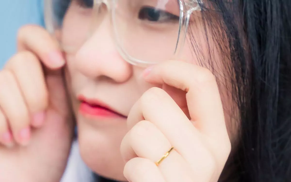 asian woman fitting her glasses frames by the cheek