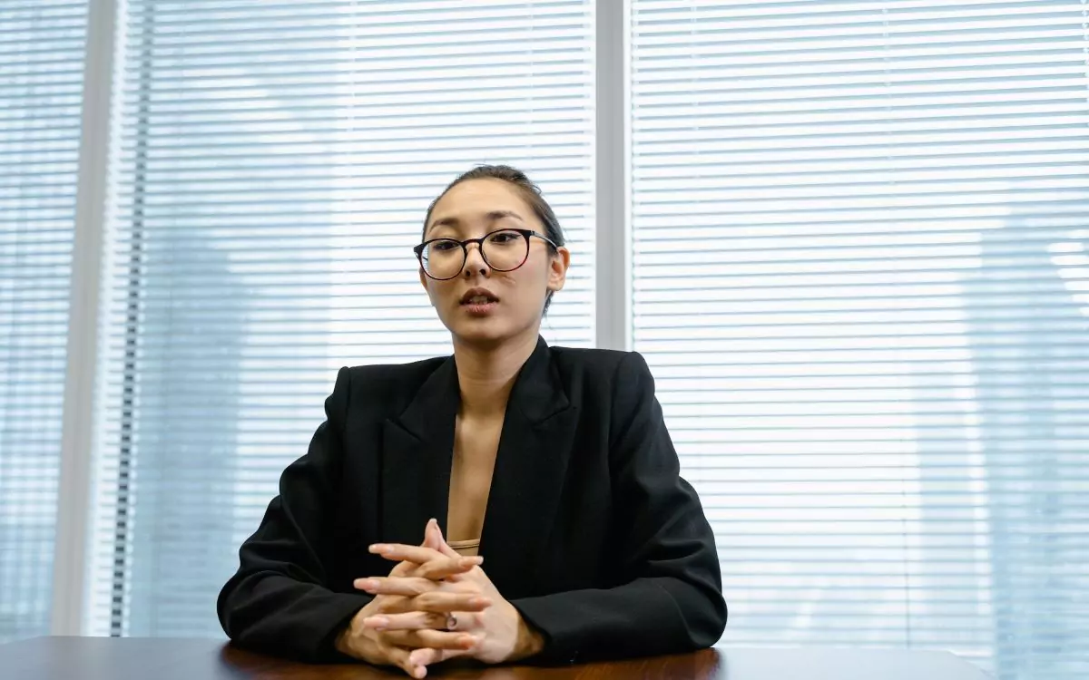 asian woman wearing a coat and glasses in an office setting