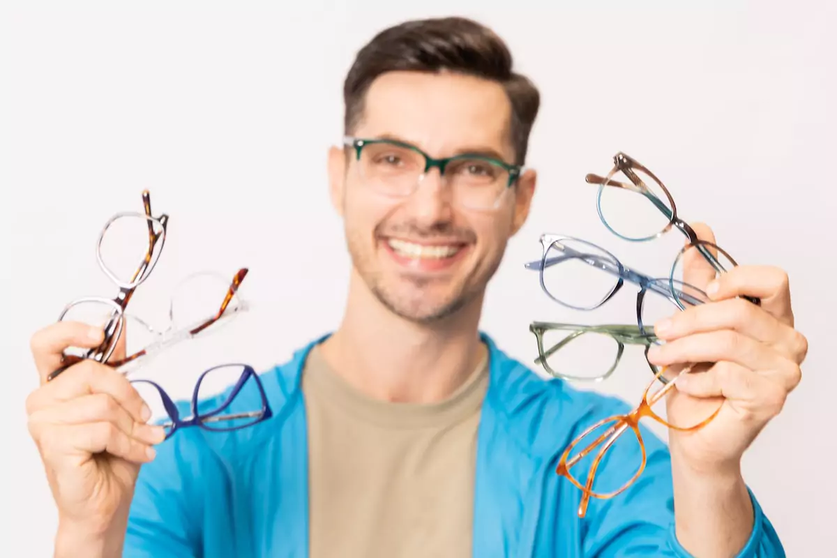 man holding multiple pair of glasses frames