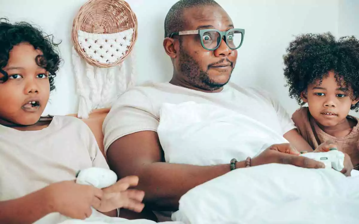 a father wears oversized dad glasses alongside his two children playing video games