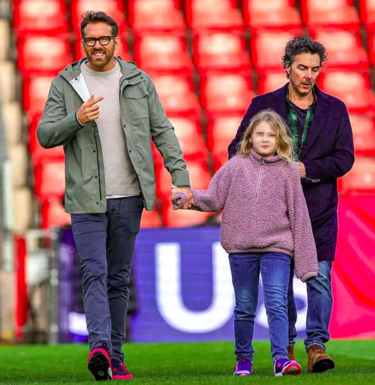 Ryan Reynolds wears thick black frames alongside his daughter on a football field