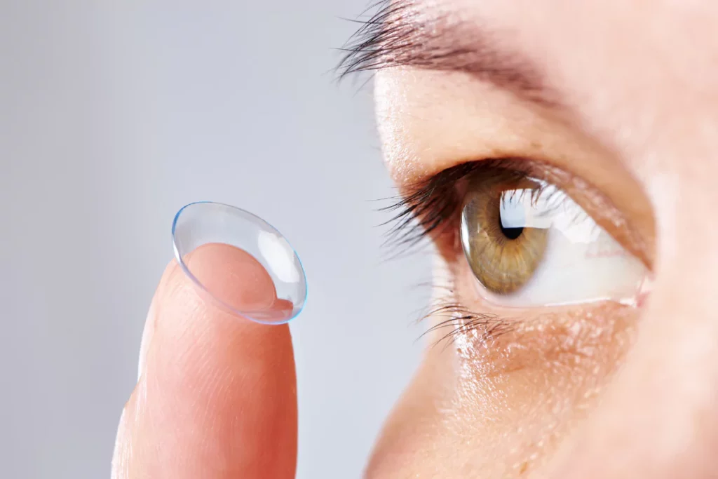 person putting on a piece of soft contact lens onto the eye