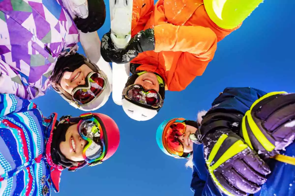 four skiers smiling with ski goggles in different styles