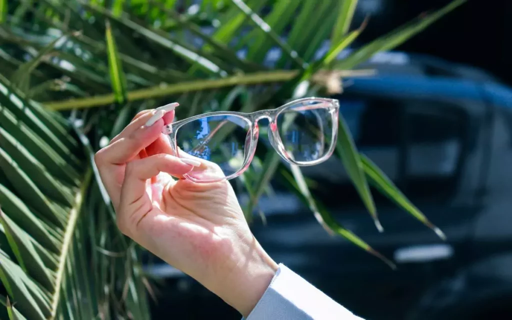 hand holding a pair of lightweight glasses with transparent frame